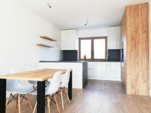 Kuchyň do L s ostrůvkem a jídelním stolem.