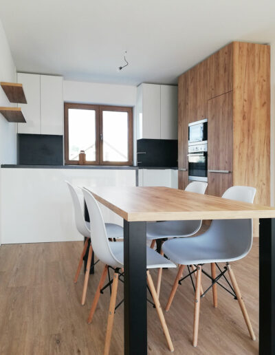 Kuchyň do L s ostrůvkem a jídelním stolem.