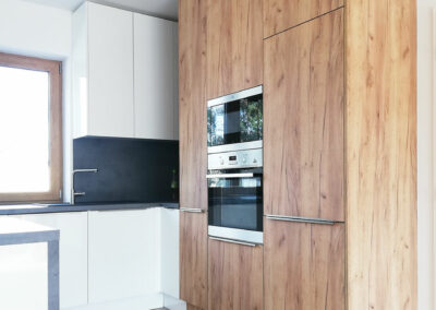 Kuchyň do L s ostrůvkem a jídelním stolem.