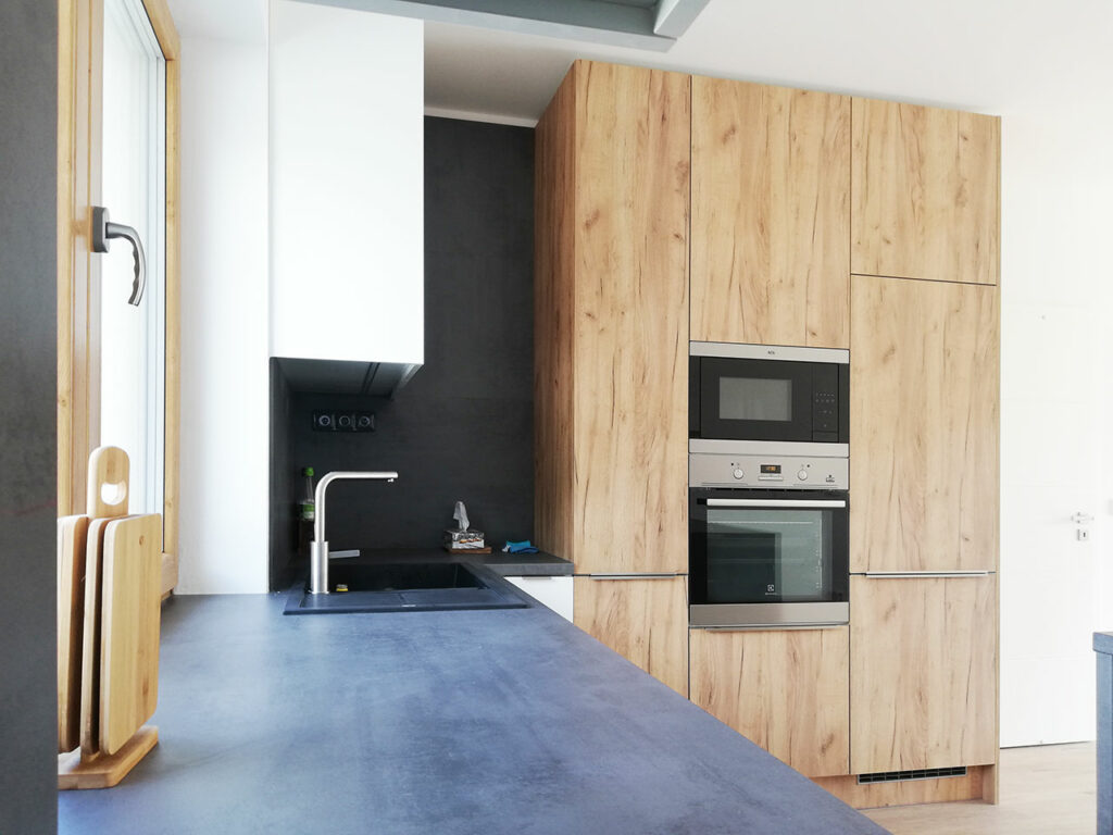 Kuchyň do L s ostrůvkem v kombinaci bílého lesku a dubu.