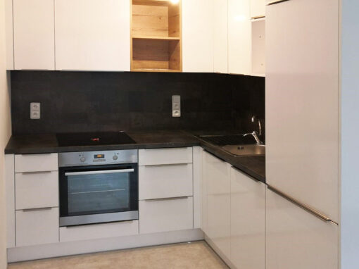 Kuchyň do L s býlým lesklými dvířky a otevřenou dřevěnou částí.