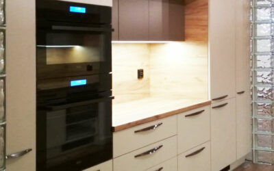 Rovná kuchyň v krémové barvě a dřevěnou pracovní deskou a zástěnou