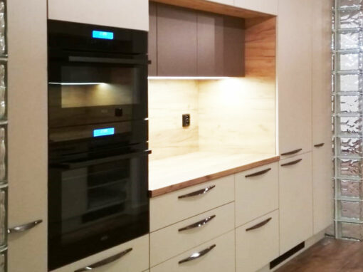 Rovná kuchyň v krémové barvě a dřevěnou pracovní deskou a zástěnou