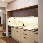 Rovná kuchyň v krémové barvě a dubovou pracovní deskou a zástěnou