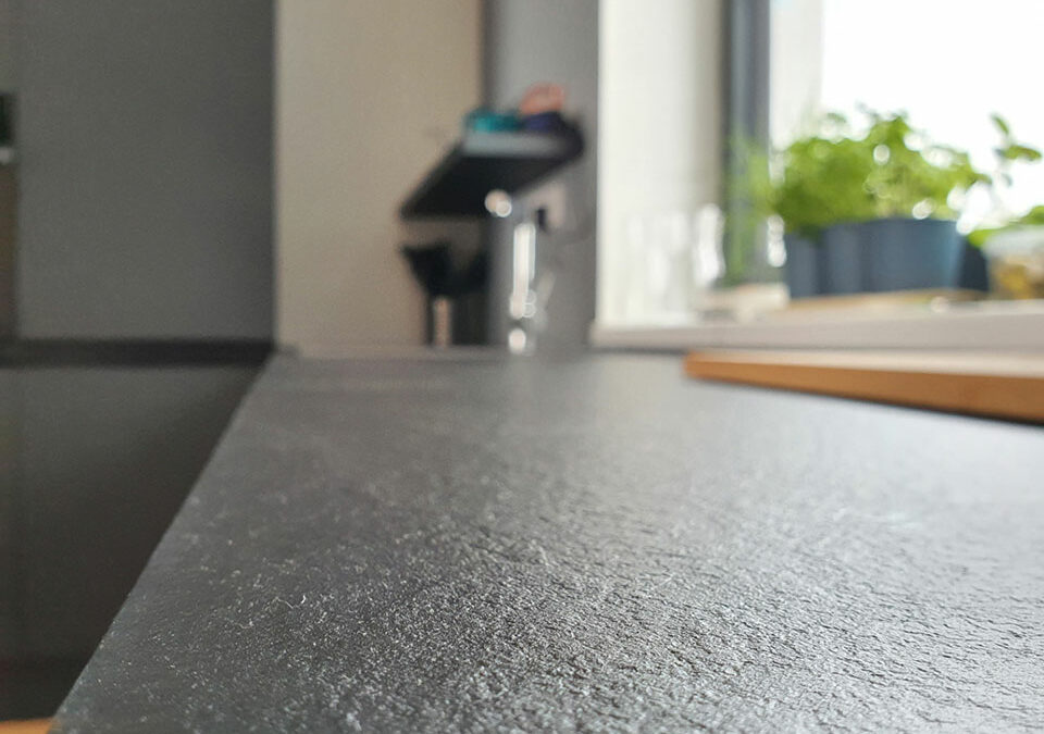 Krásná kuchyň v kombinaci bílého lesku a černého matu. Vše završeno tenkou pracovní deskou z kompaktního laminátu a úchytkami lakovanými v barvách kuchyně.