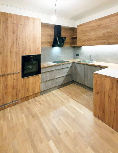 Velká kuchyň do U v kombinaci dub a betonová stěrka.