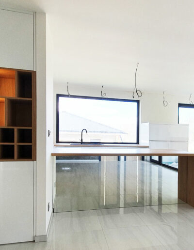 Kuchyň do U se zády ostrůvku ze zrcadla a podsvícenou vinotékou.