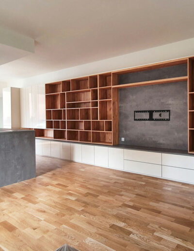 Obývací stěna v krémové lesklé barvě, otevřenými policemi a kuchyňským ostrůvkem.
