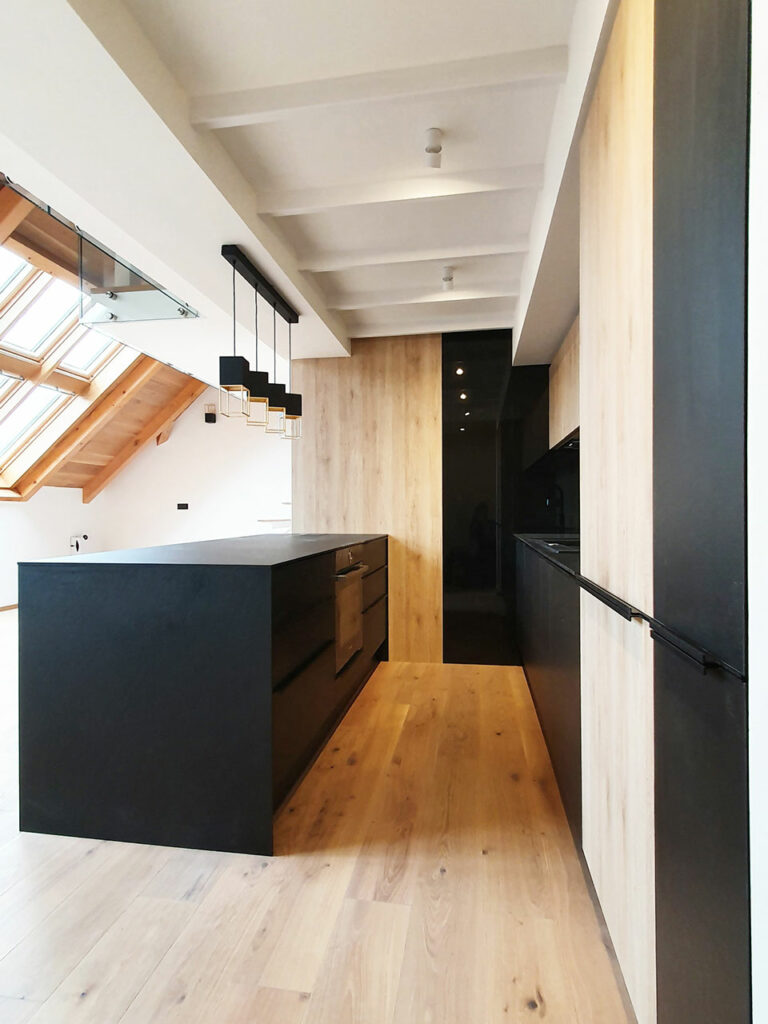 Kuchyň do podkrovního bytu v kombinaci černé matné a přírodní dub.