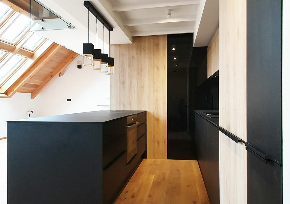 Kuchyň do podkrovního bytu v kombinaci černé matné a přírodní dub.